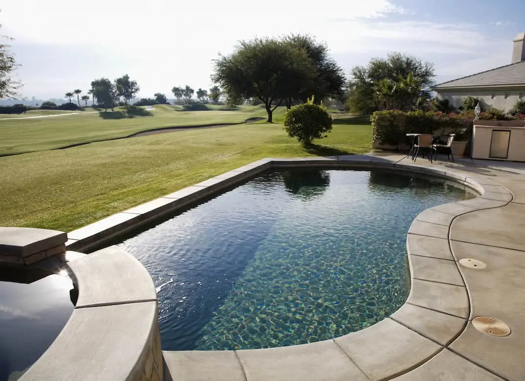 Modern gray stamped concrete pool with views of the golf field.