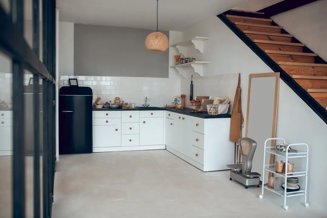 Micro-cement floor in a kitchen equipped with tiles on the walls and decorated in a classic style