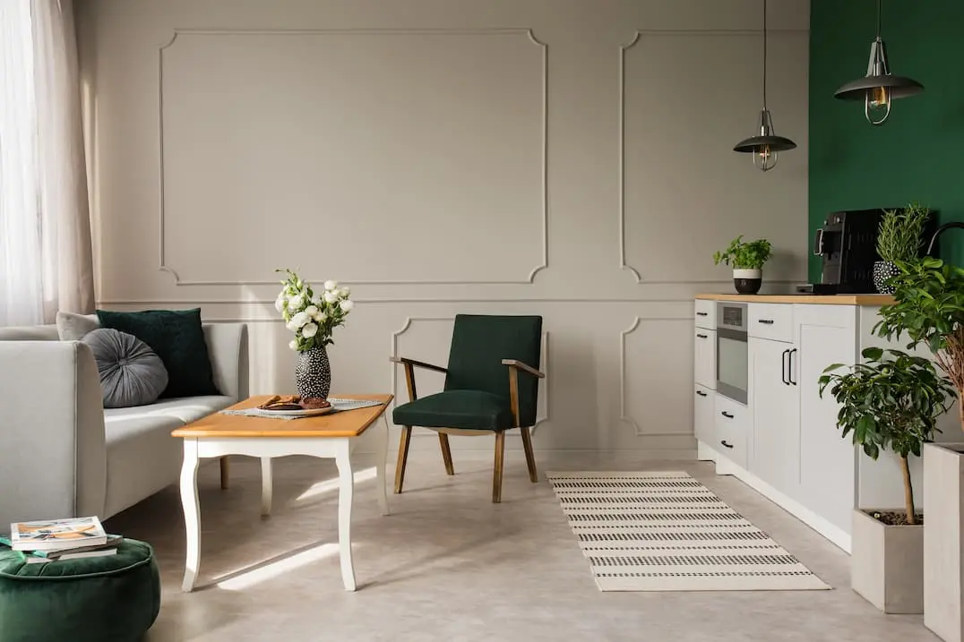 Kitchen joined to living room with wall covered in green decorative paint