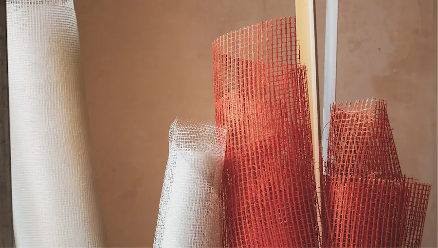 White and red fiberglass mesh with an earth-colored wall in the background