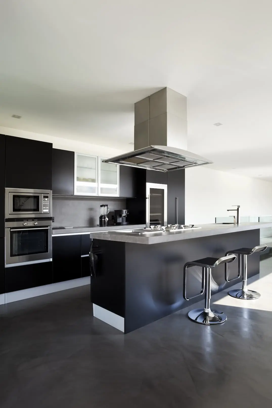 Black kitchen with island and lime mortar floor