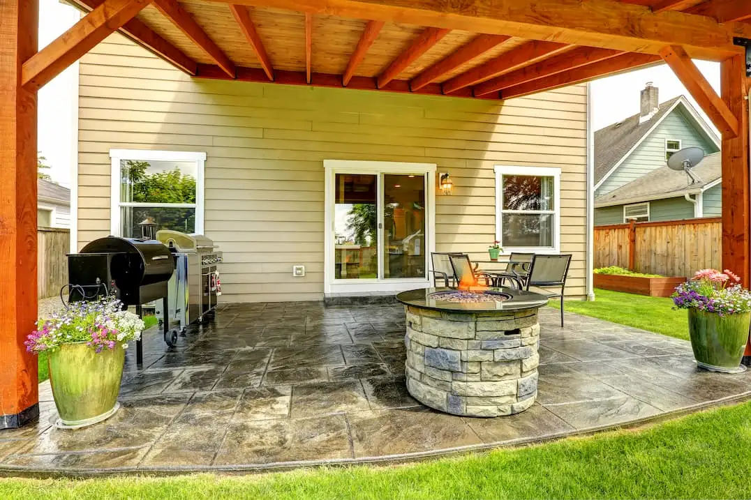 Vivienda de madera con zona de terraza con barbacoa y suelo de hormigón impreso