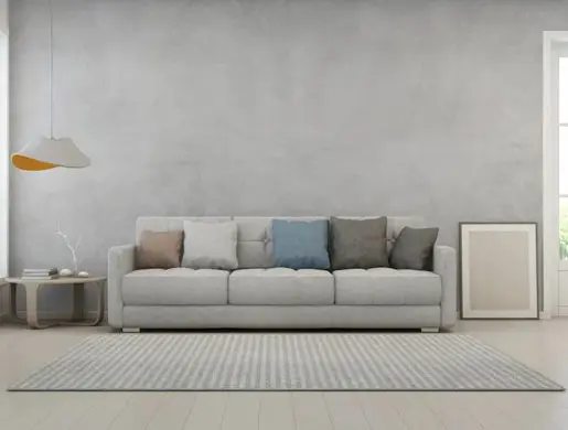 Sala de estar en tonos claros con pared de microcemento en Cádiz
