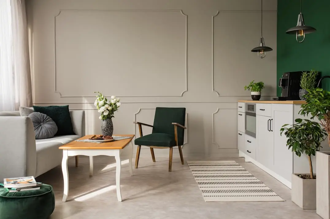 Elutoa ja väikese köögi ühendus, kus on diivan ja väike laud ning roheline sein