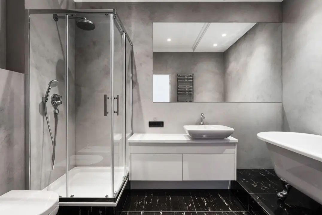 Mikrotsemendiga vannituba, mille seinad on kaetud hallides toonides, et rõhutada ruumi põhjamaist dekoratsiooni.