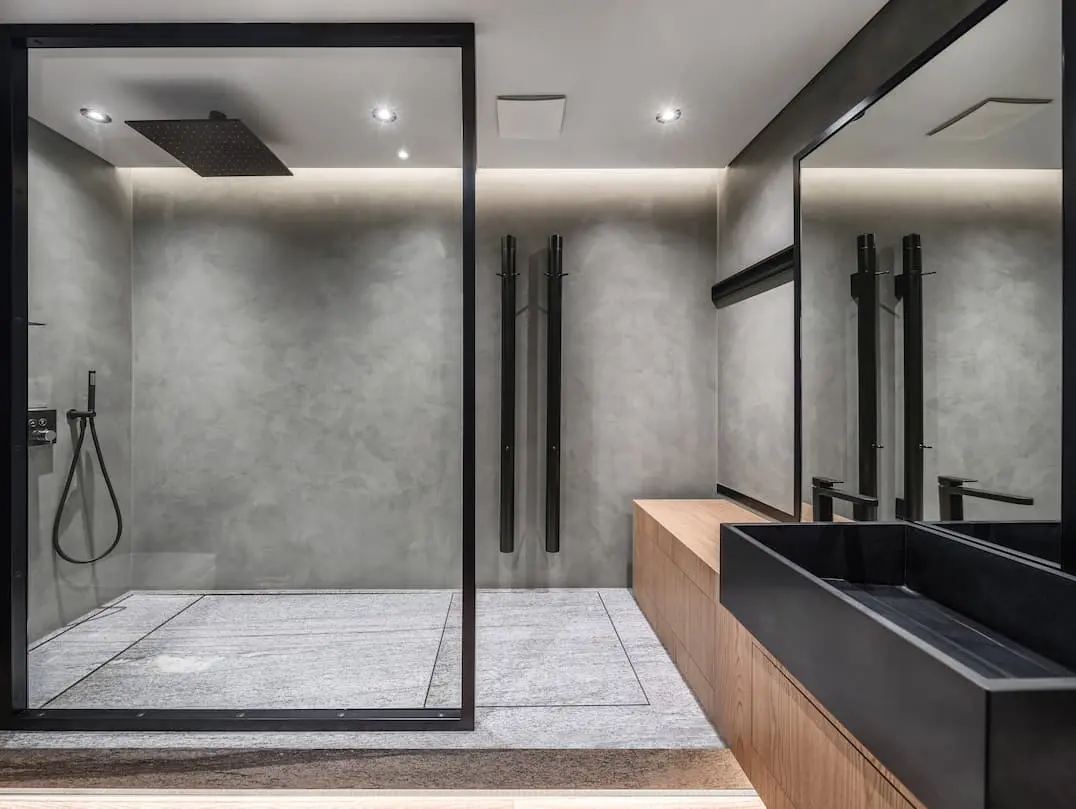 Kylpyhuone, jossa on suihku ja seinä, joka on koristeltu koristeellisella betonilla