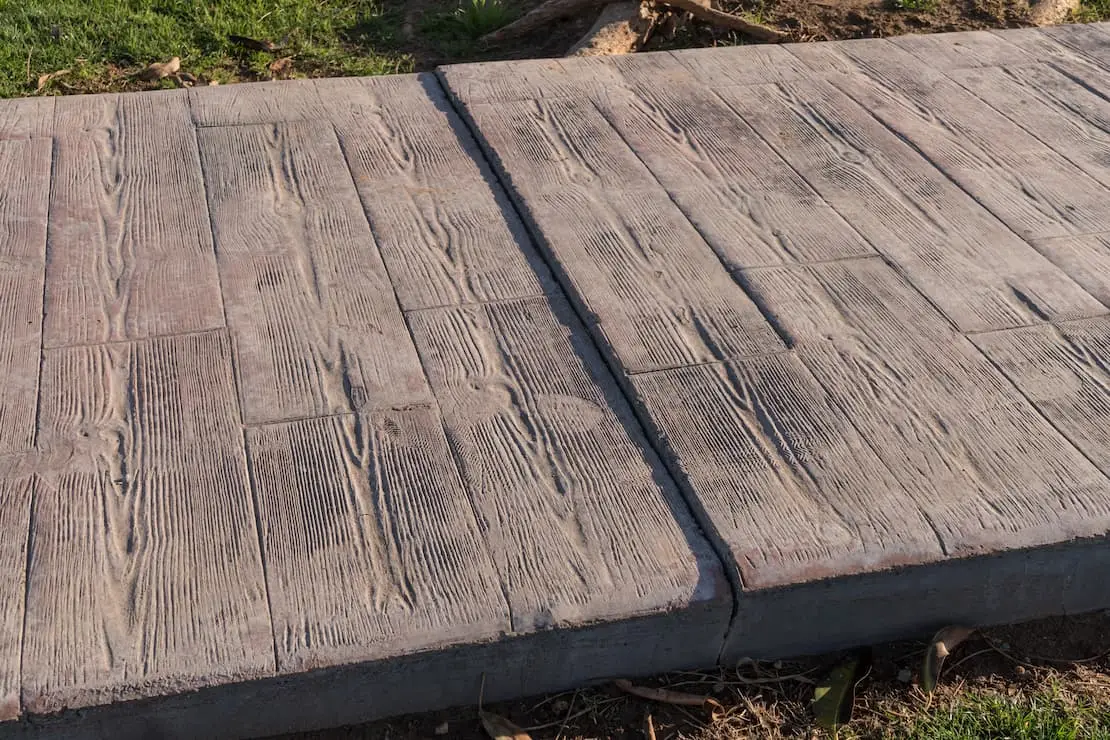 Jardin avec allée décorée en béton ciré imitation bois.