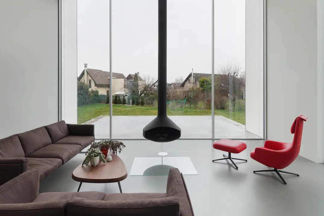 Salon de grandes dimensions joint par une véranda à une terrasse en béton ciré gris.