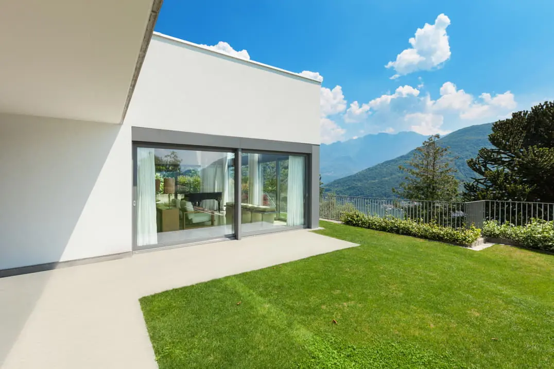 Béton ciré sur la terrasse d'une maison de luxe avec jardin et grandes fenêtres