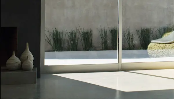 Cire de protection pour béton ciré appliquée sur le sol d'une maison avec vue sur l'extérieur et des tons gris