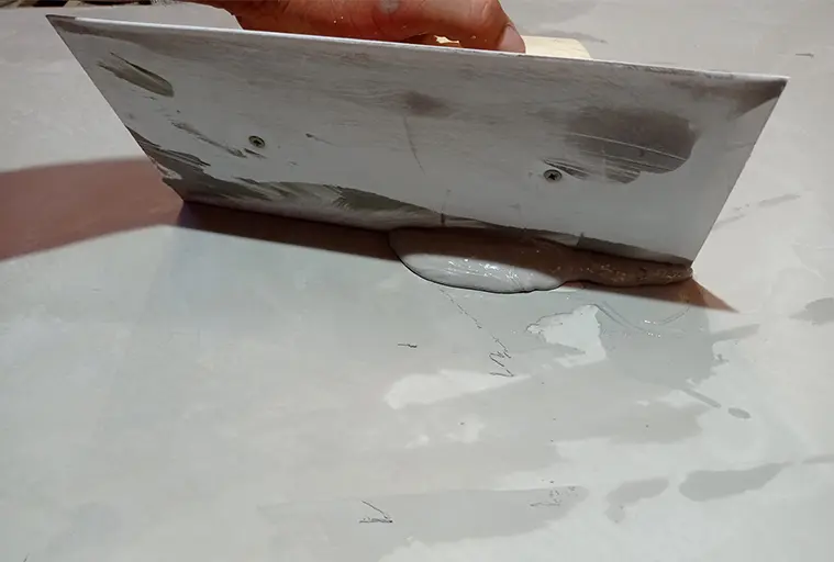 Gumi spatulával történő mikrocement alkalmazása a padlón