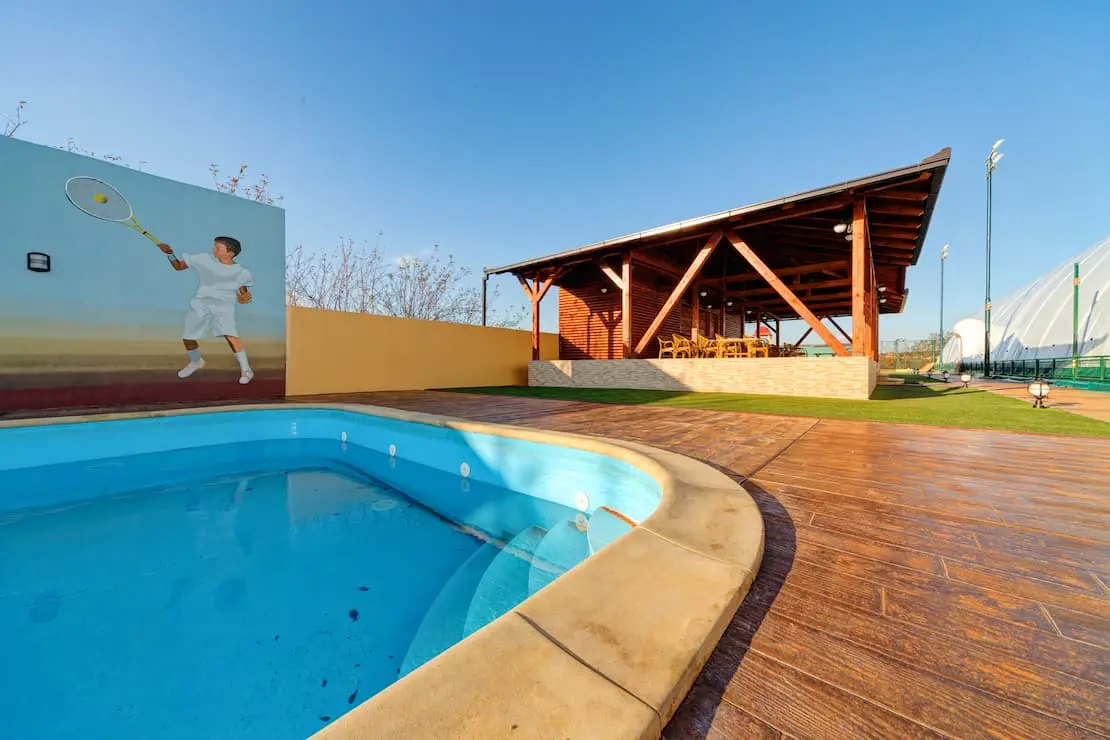 Klub tenis dengan kolam renang dan sekelilingnya lantai beton cetakan imitasi kayu.