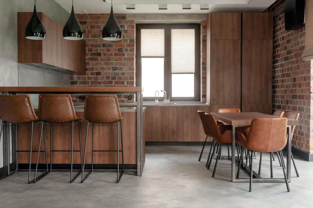 Virtuvė su matomais plytų sienomis ir pilka microcemento grindys