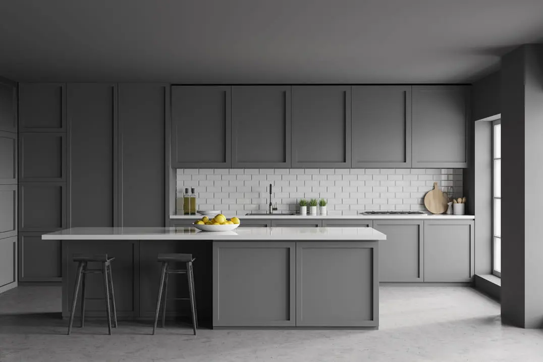 Virtuvė su pilkais spintų spalvomis ir mikrocemento grindimis