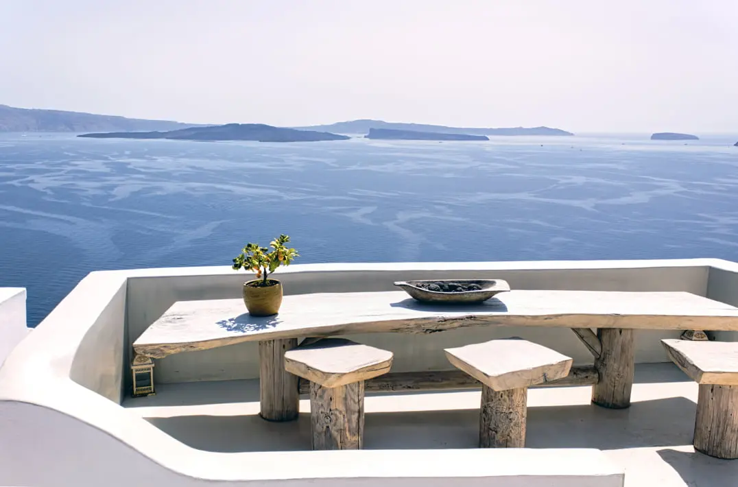 Teres mikrocement dengan pemandangan laut dan meja serta bangku kayu.