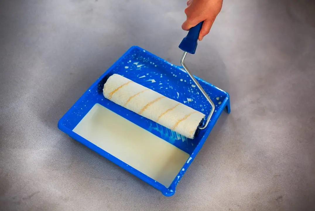 Roller om polyurethaanlak op een blauwe container aan te brengen