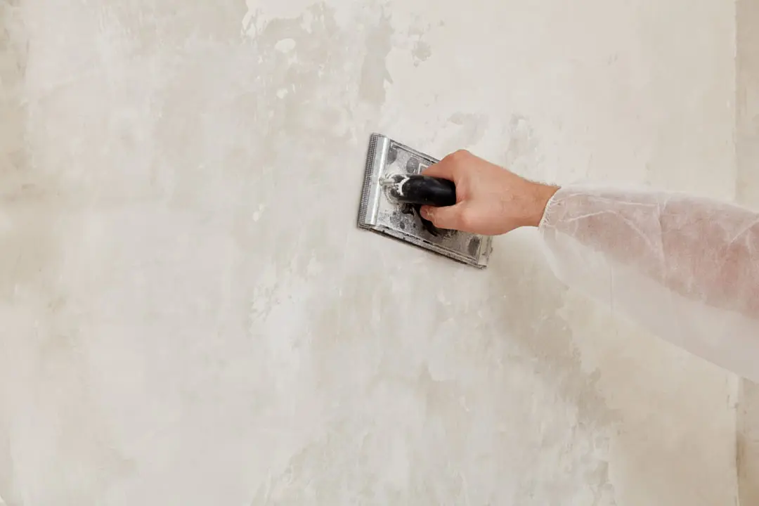 Profissional a aplicar microcimento na parede com espátula