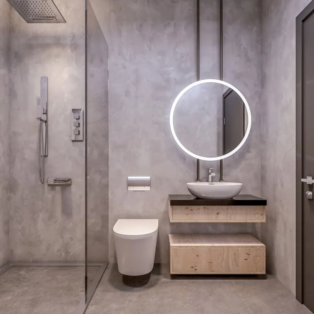 Microcemento trong một phòng tắm nhỏ được trang trí với các tông màu ấm và một chiếc tủ đơn giản bằng gỗ dưới chậu rửa